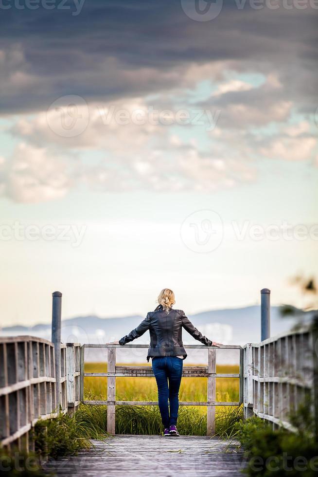 Mujer joven solitaria mirando el increíble paisaje tranquilo desde un balcón de madera foto