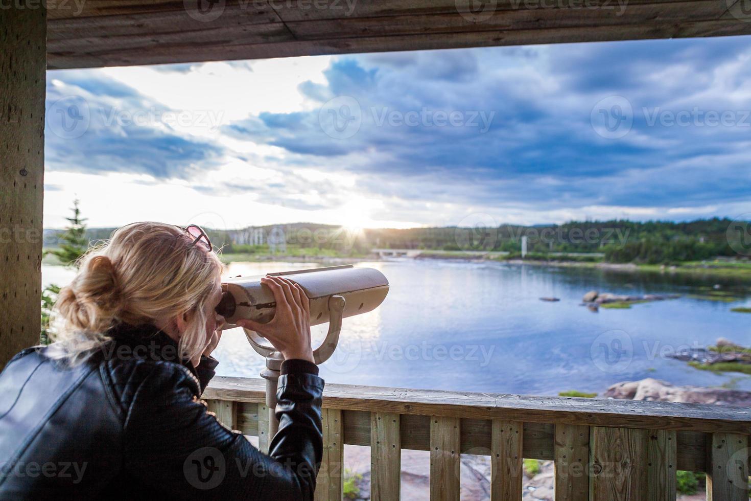 Young Woman Looking at the Amazing Nature Through a Binocular in a Observation Tower photo