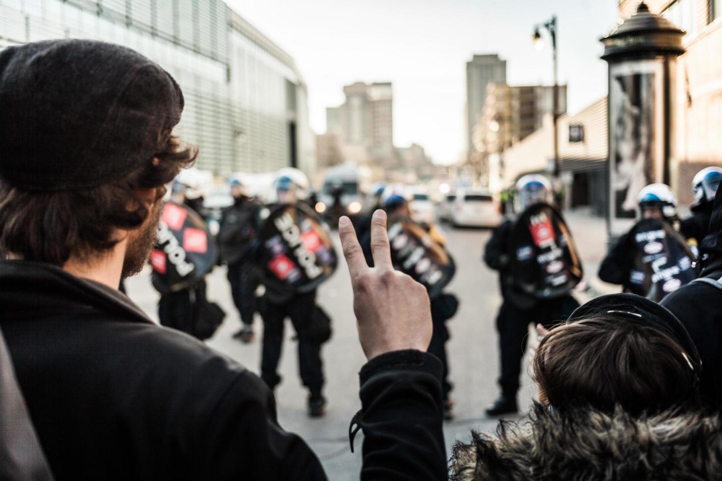 Montreal, Canadá 02 de abril de 2015 - hombre haciendo un signo de paz frente a la policía foto