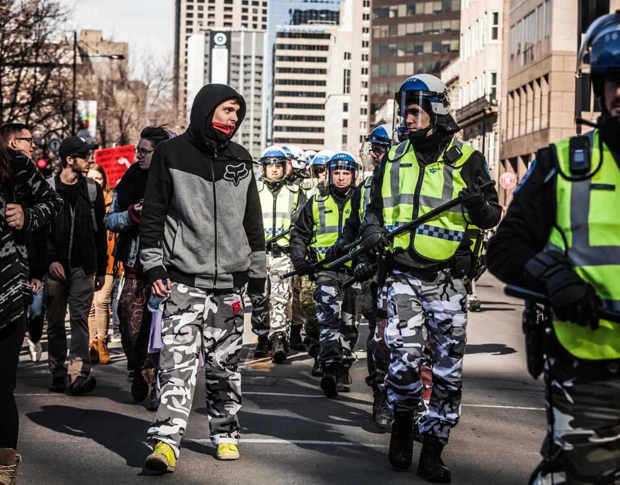 Montreal, Canadá 02 de abril de 2015 - policía y manifestante mirándose a los ojos y vistiendo los mismos pantalones militares foto