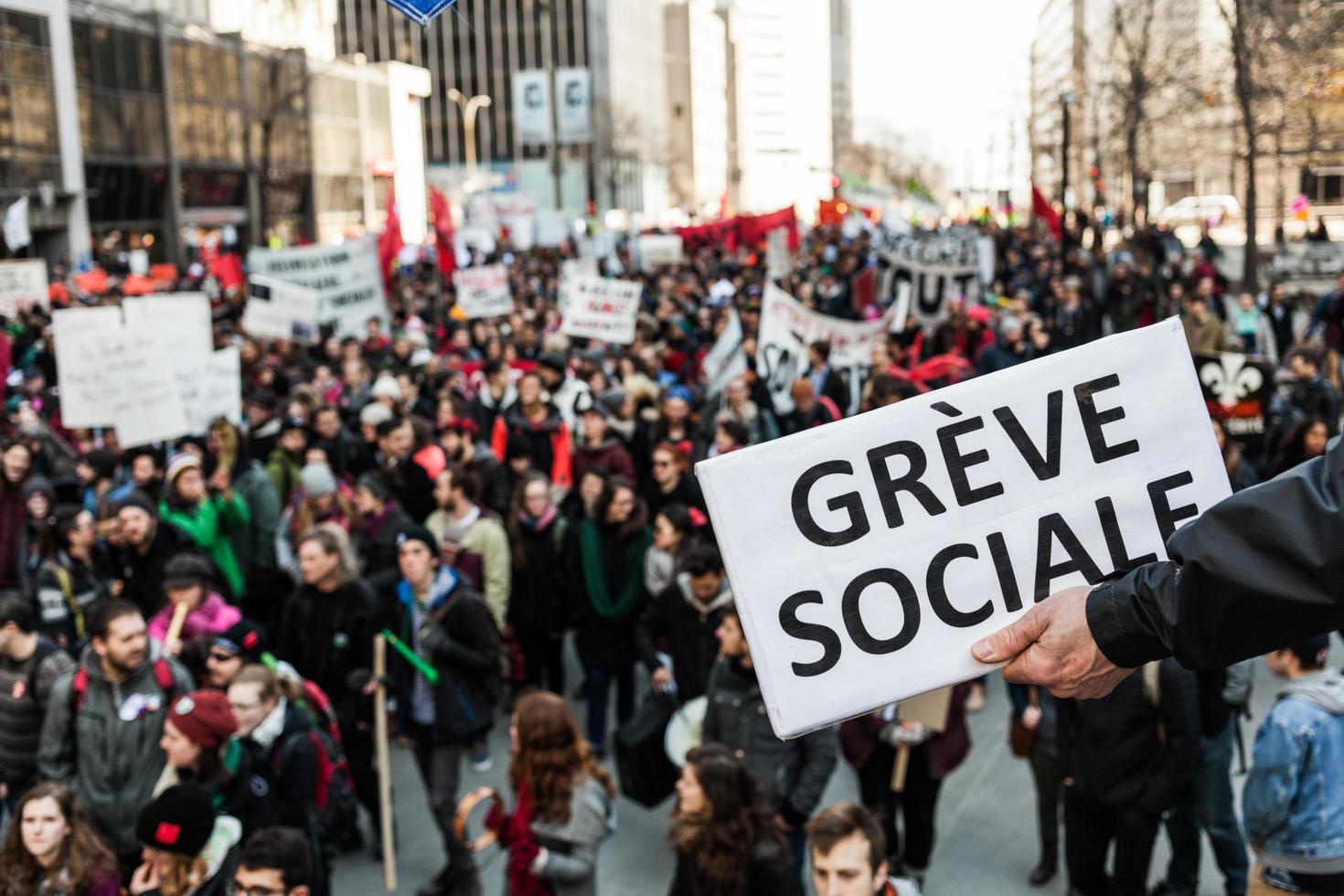 Montreal, Canadá, 02 de abril de 2015: alguien que sostiene un suspiro y dice Greve sociale con un manifestante borroso en el fondo. foto