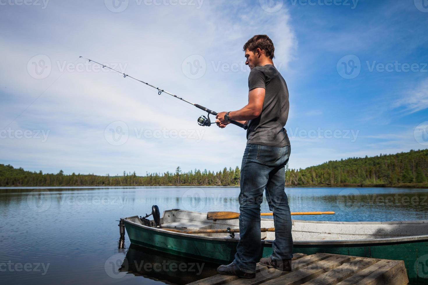 adulto joven pescando en un lago tranquilo foto