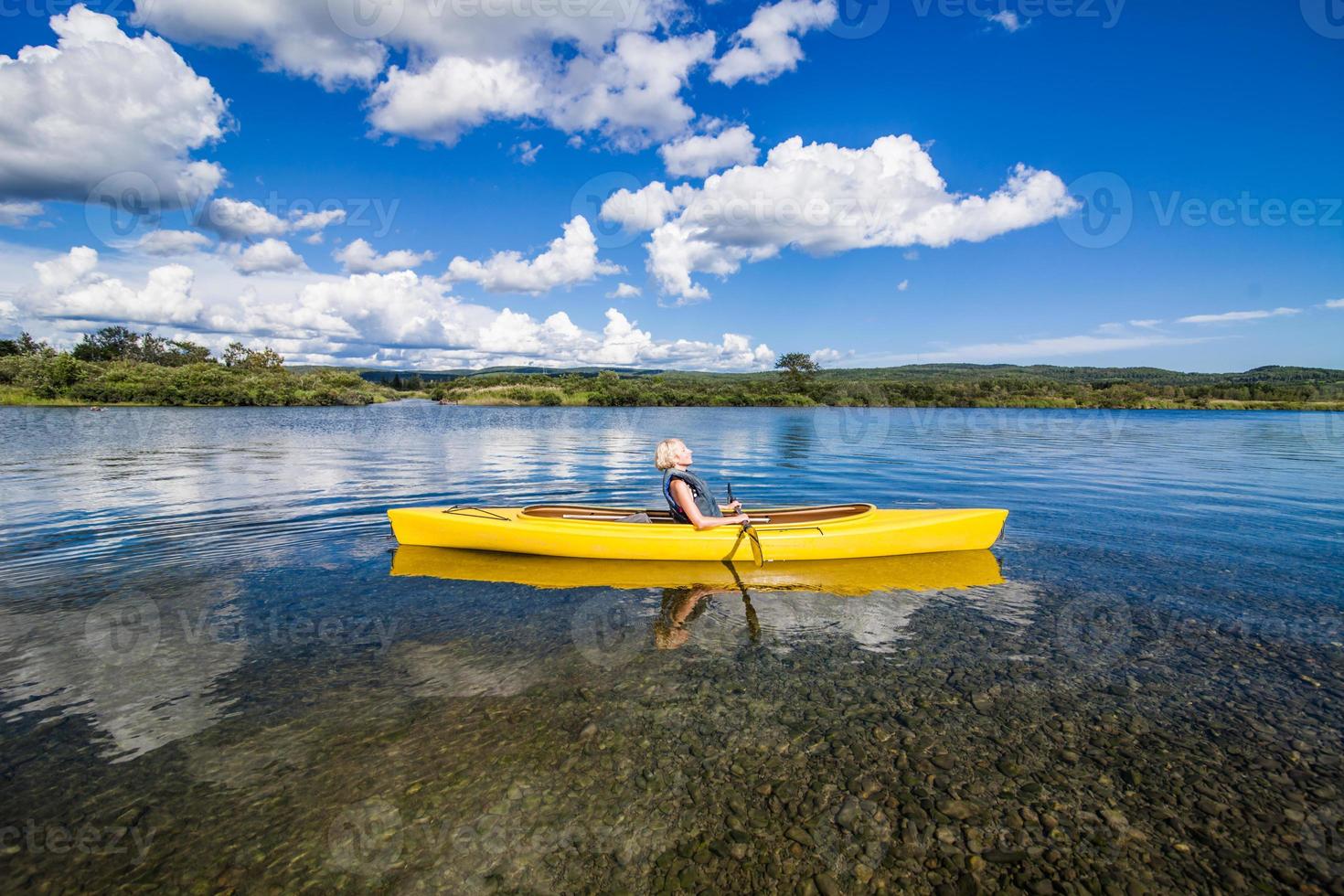 Río tranquilo y mujer relajante en un kayak foto