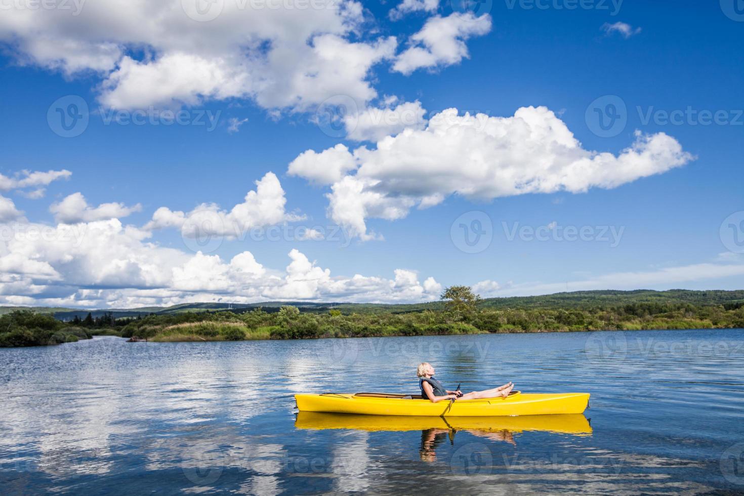 Río tranquilo y mujer relajante en un kayak foto