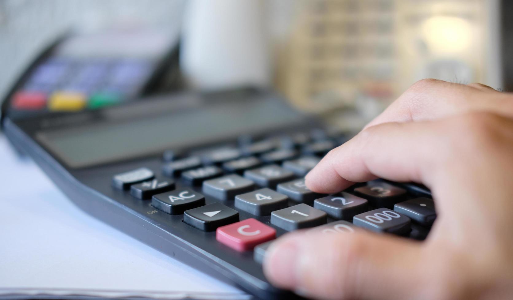 In her office, a businesswoman calculates her finances using a calculator and a notebook. photo