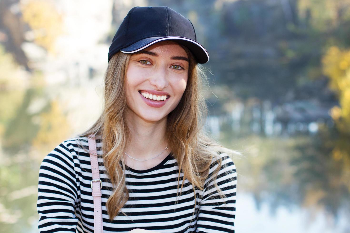 hermosa joven activa sobre un fondo de una hermosa vista del bosque y las rocas. Chica con gorra y ropa casual - concepto de vida activa foto