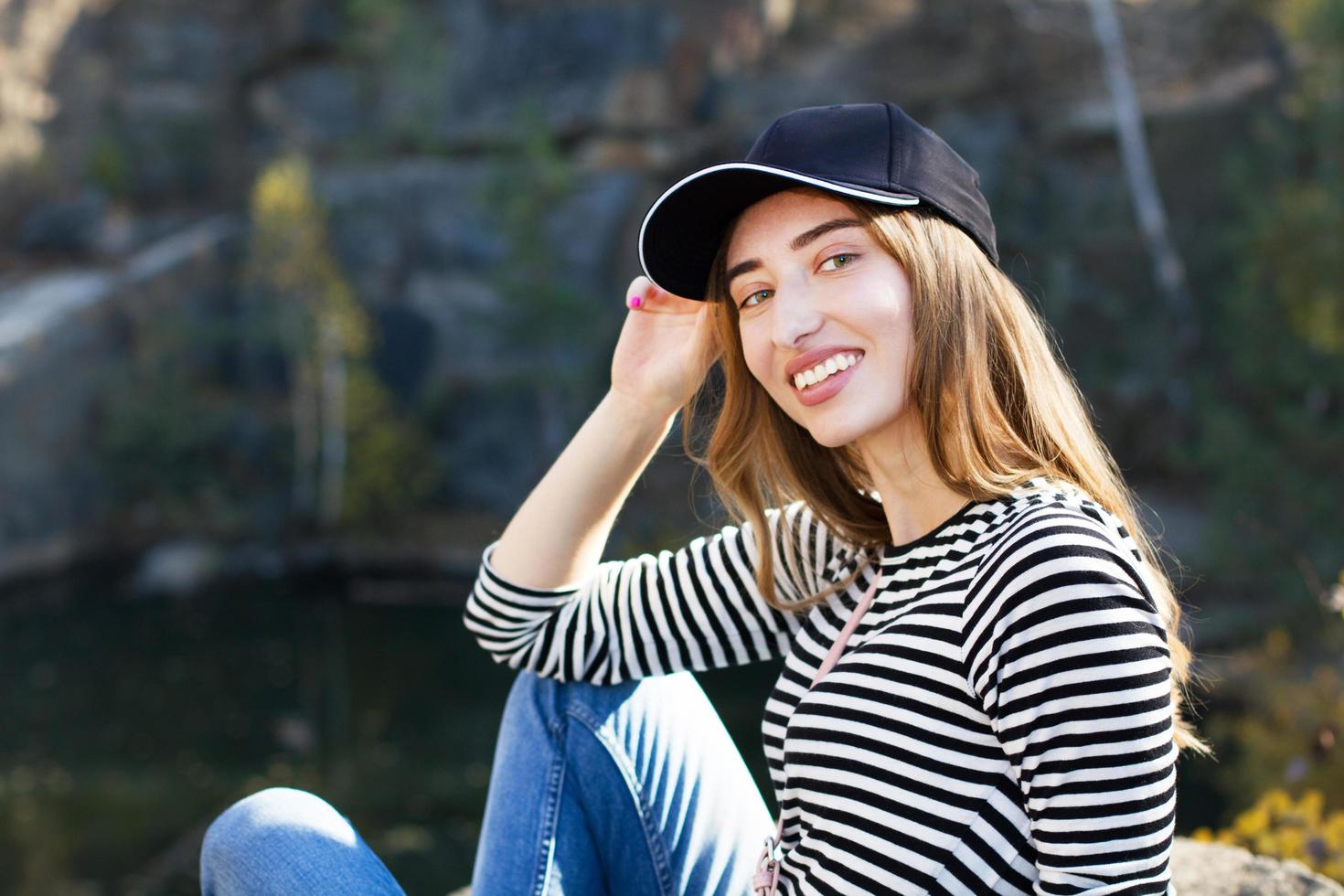 mujer joven feliz en una elegante chaqueta posando sobre un fondo de montañas y bosques - concepto de descanso activo. foto