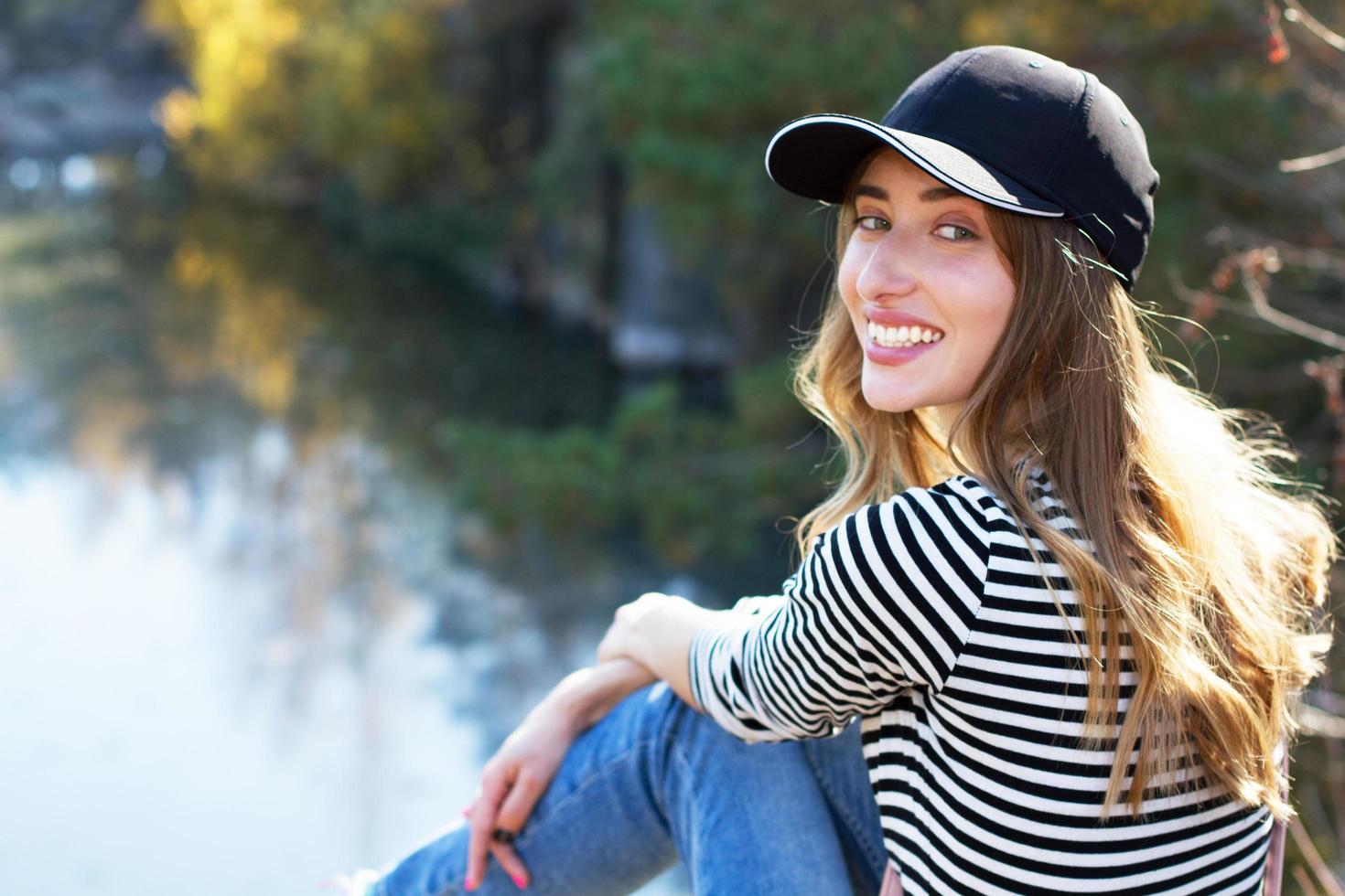 Beautiful smile hipster girl in a black cap on a background of autumn forest photo