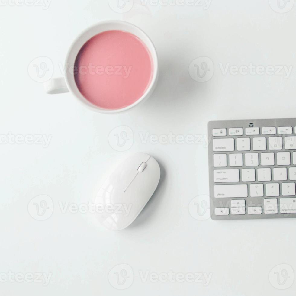 espacio de trabajo blanco con cuaderno rosa claro y flor blanca con café en la mesa blanca. foto