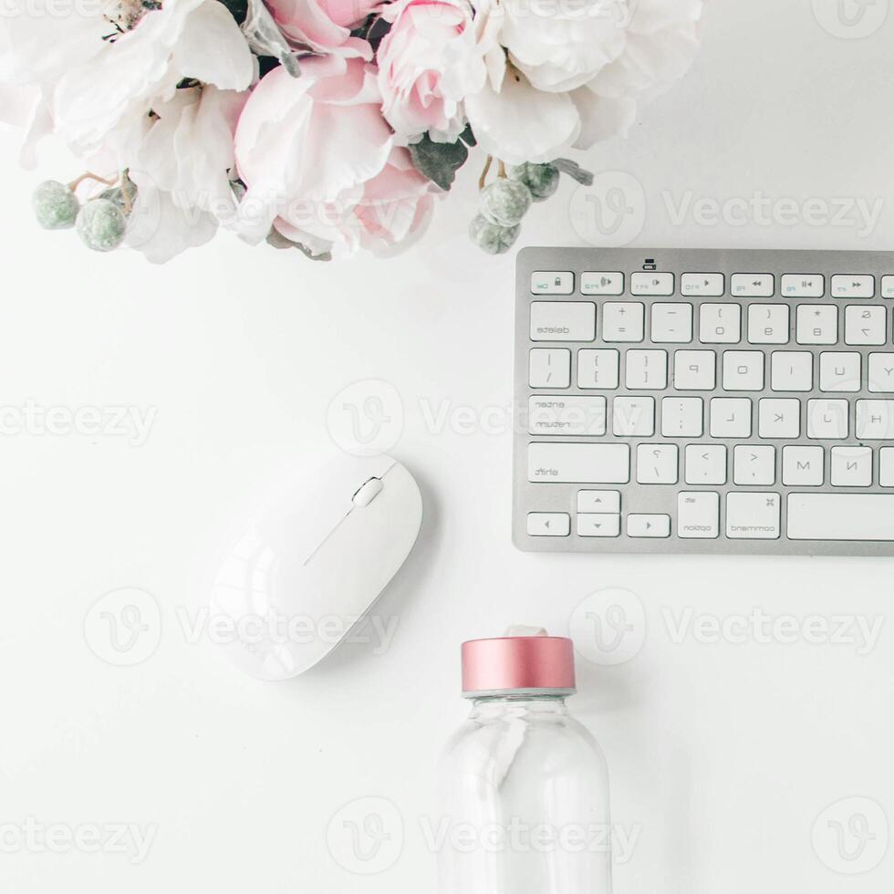 espacio de trabajo blanco con cuaderno rosa claro y flor blanca con café en la mesa blanca. foto