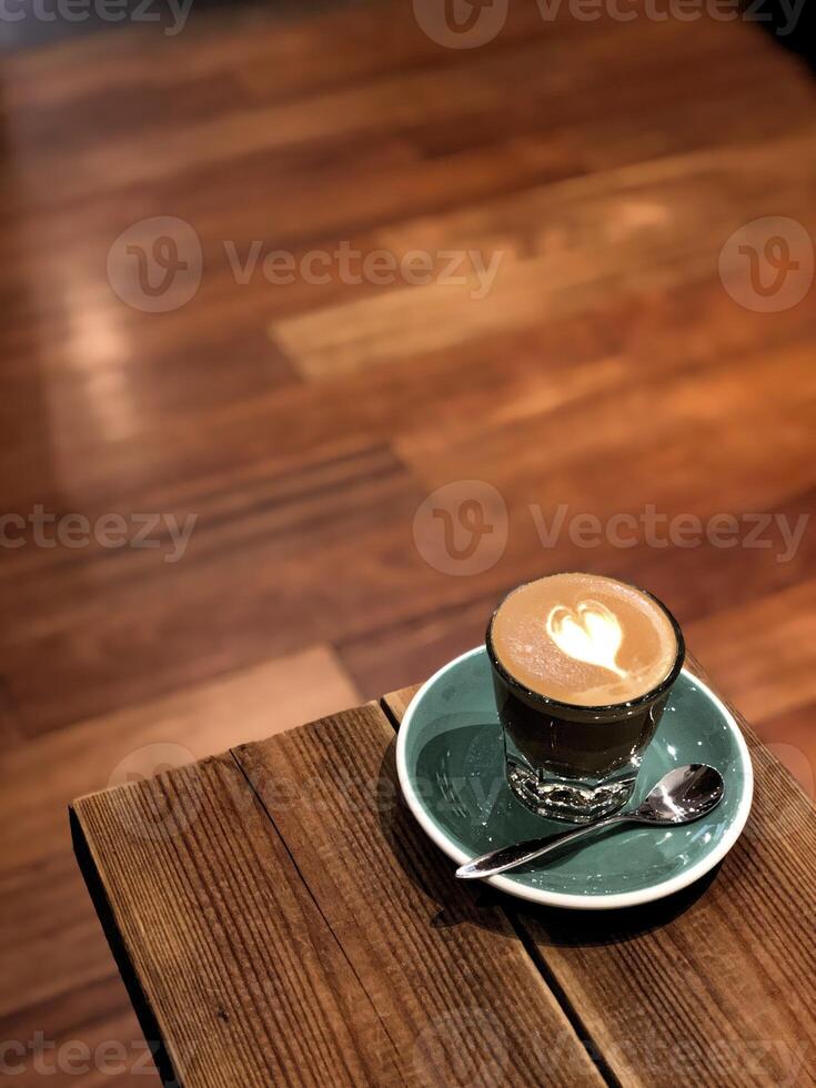 Café capuchino con forma de corazón en un vaso azul sobre la mesa foto