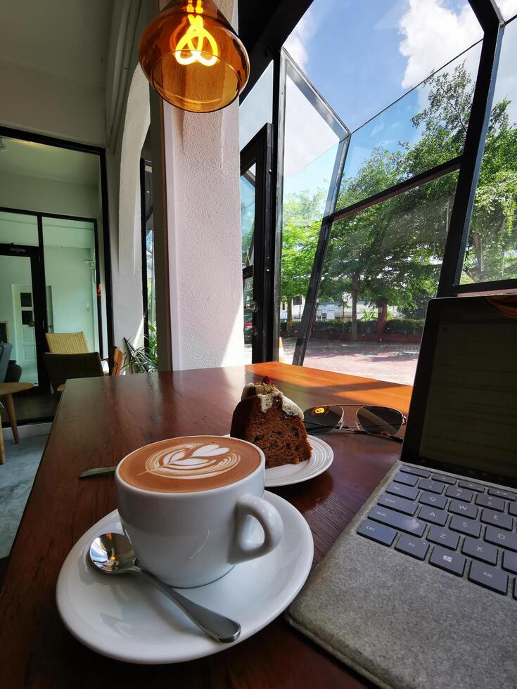 café con leche con bocadillos de pan y una computadora portátil con un estacionamiento en el fondo foto