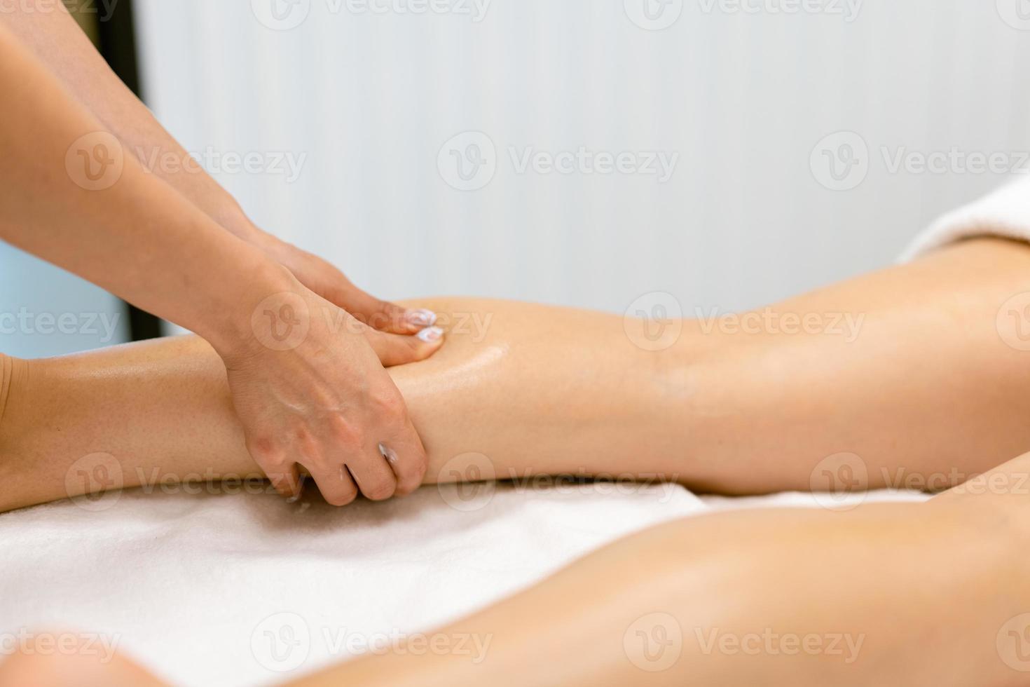 Middle-aged woman having a leg massage in a beauty salon. photo