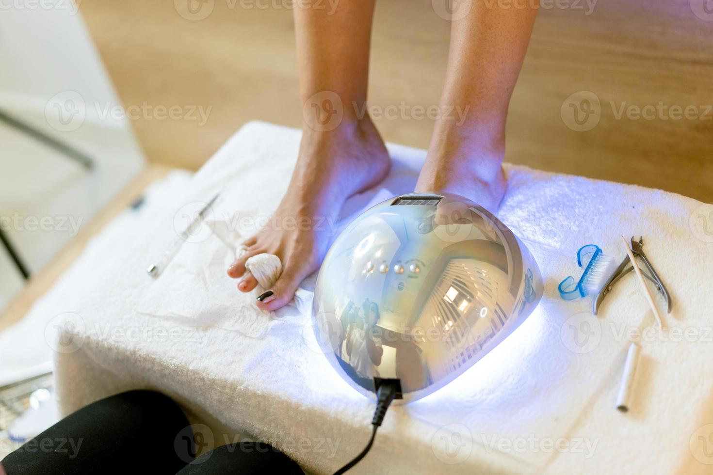 Beautician giving a pedicure painting her client's nails in a beauty centre. photo