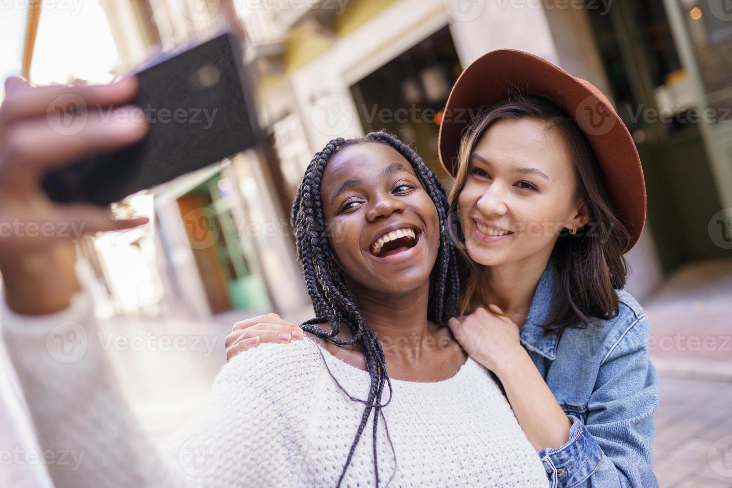 Dos hermosas mujeres multiétnicas haciendo selfie y haciendo muecas. foto