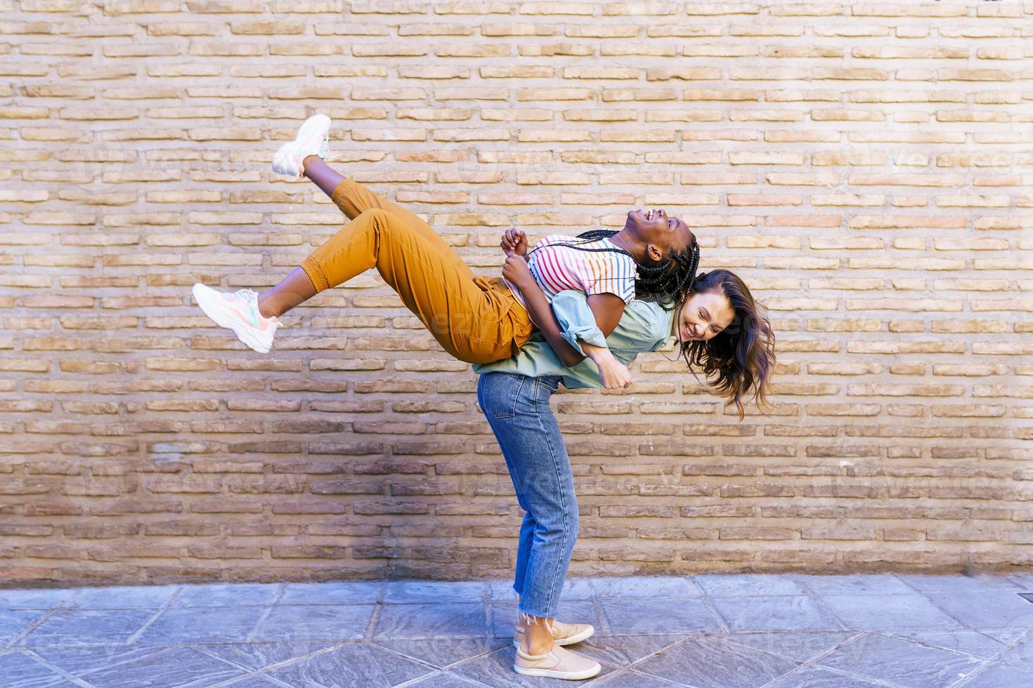 divertida mujer multiétnica que lleva a su mejor amigo a cuestas foto