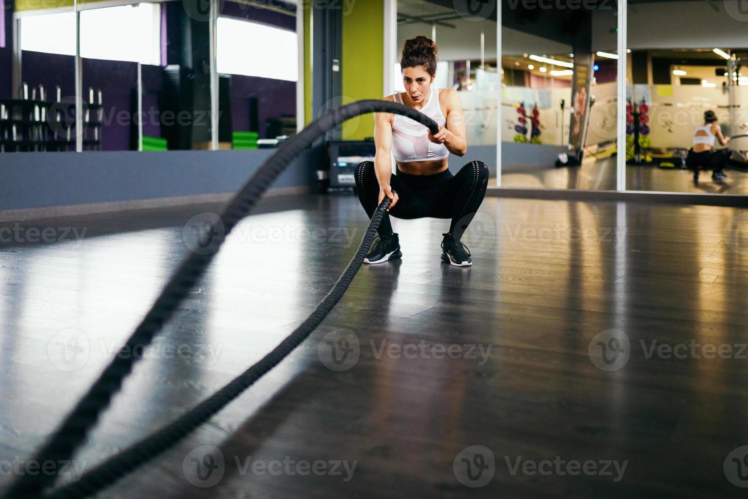 Mujer joven y atlética con cuerdas de entrenamiento en un gimnasio. foto