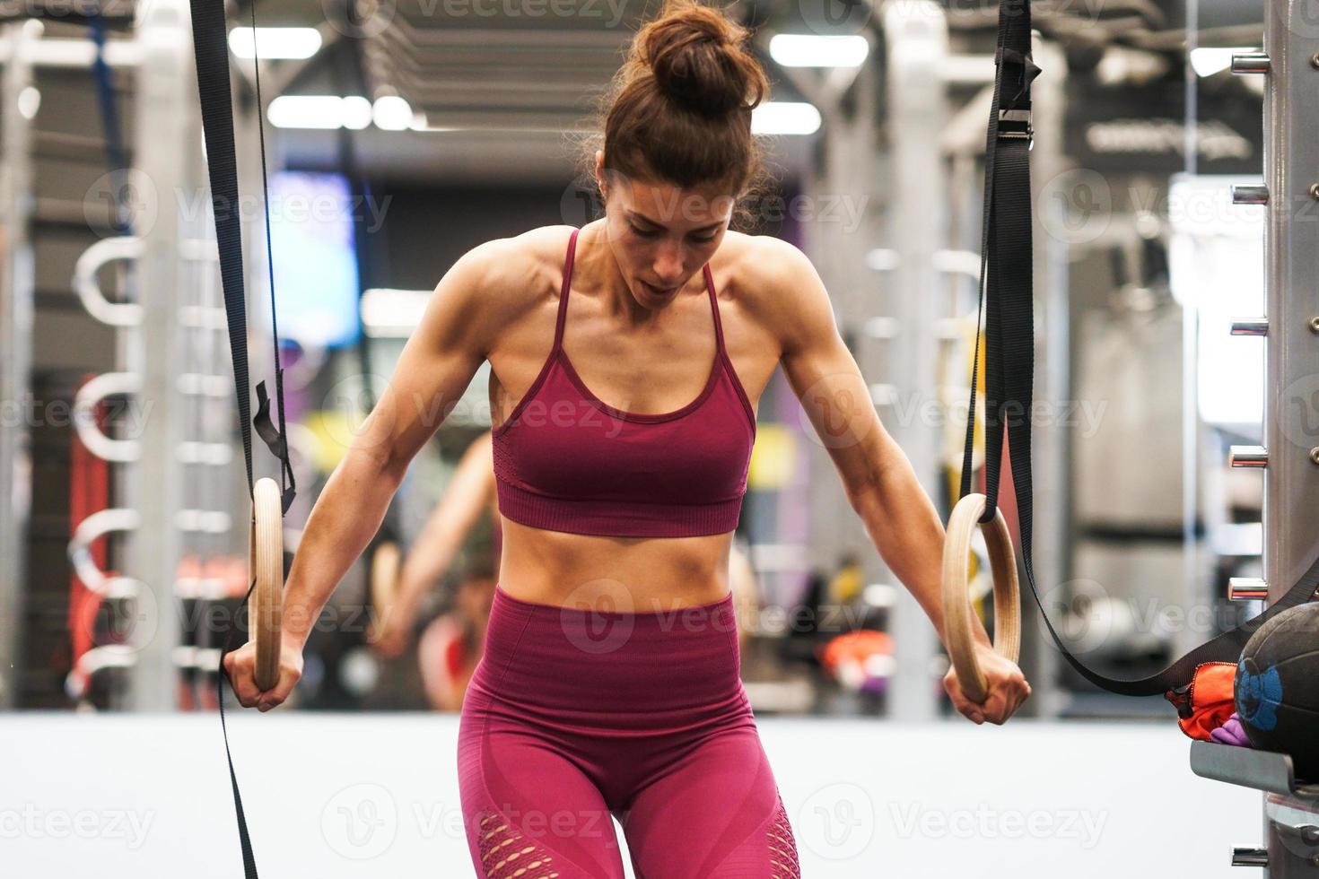 Mujer atlética haciendo algunos ejercicios de pull up en los anillos de gimnasia foto