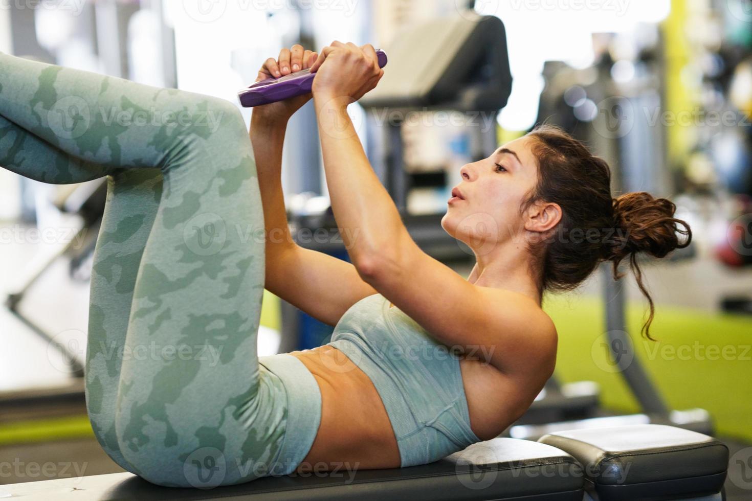 Young sportswoman on yoga mat doing situps in gym. photo