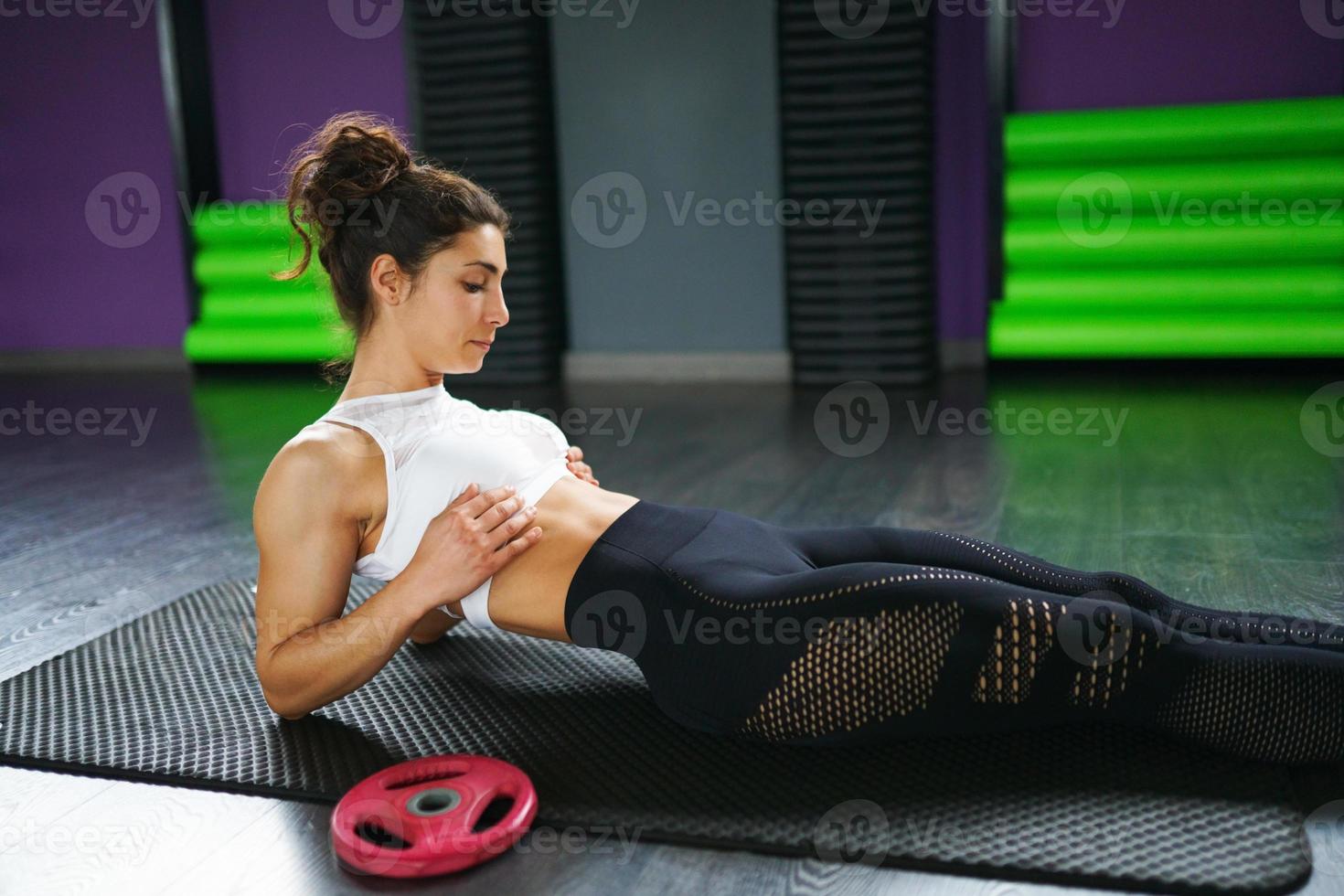 joven deportista en estera de yoga haciendo abdominales en el gimnasio. foto