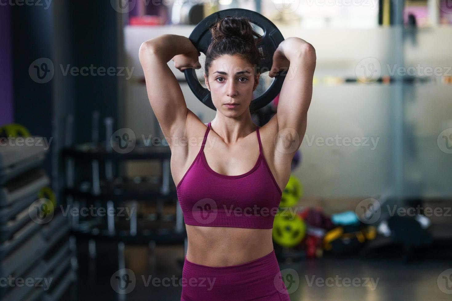 Mujer atlética haciendo flexiones de tríceps con una placa de barra foto