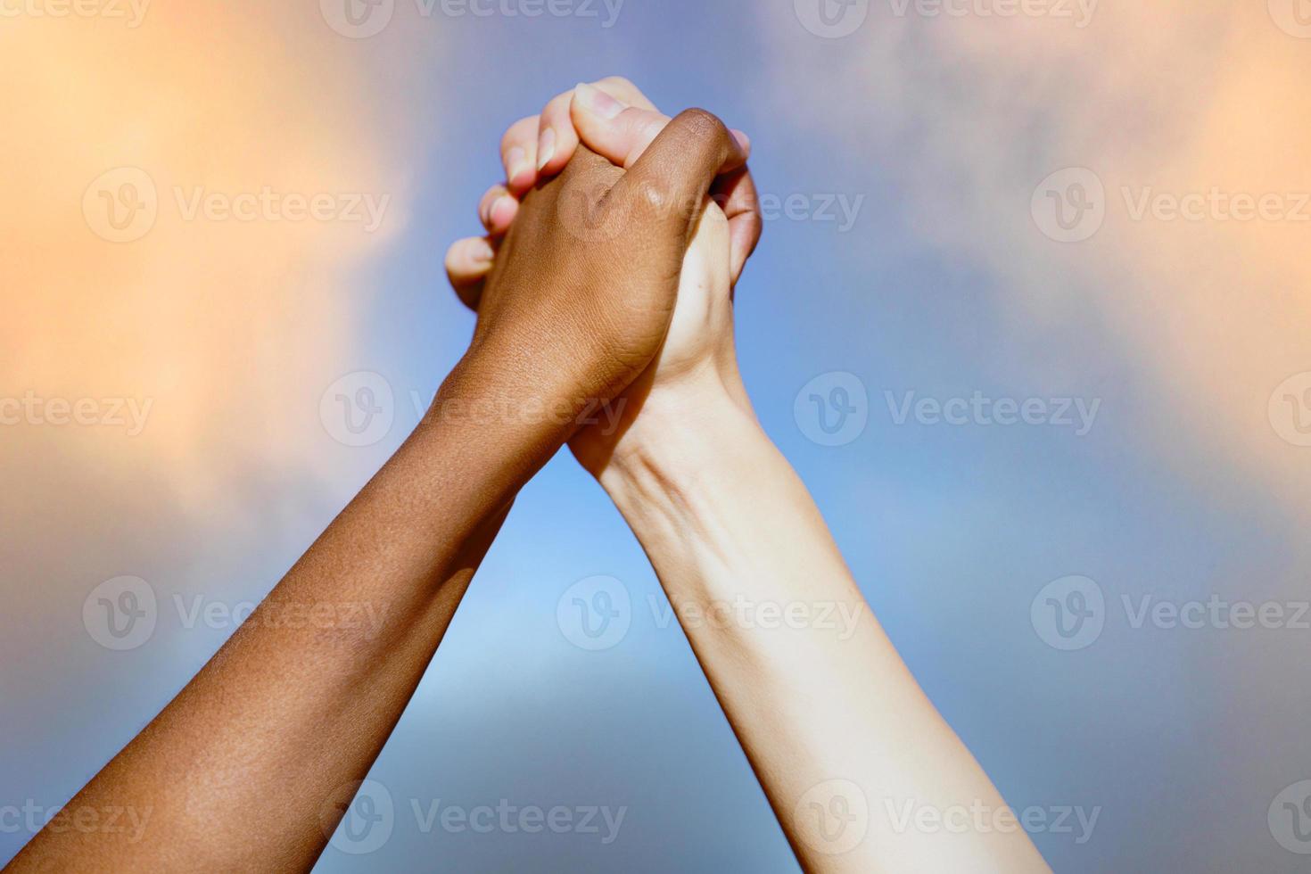 Multiethnic women's hands together against cloudy sky. photo