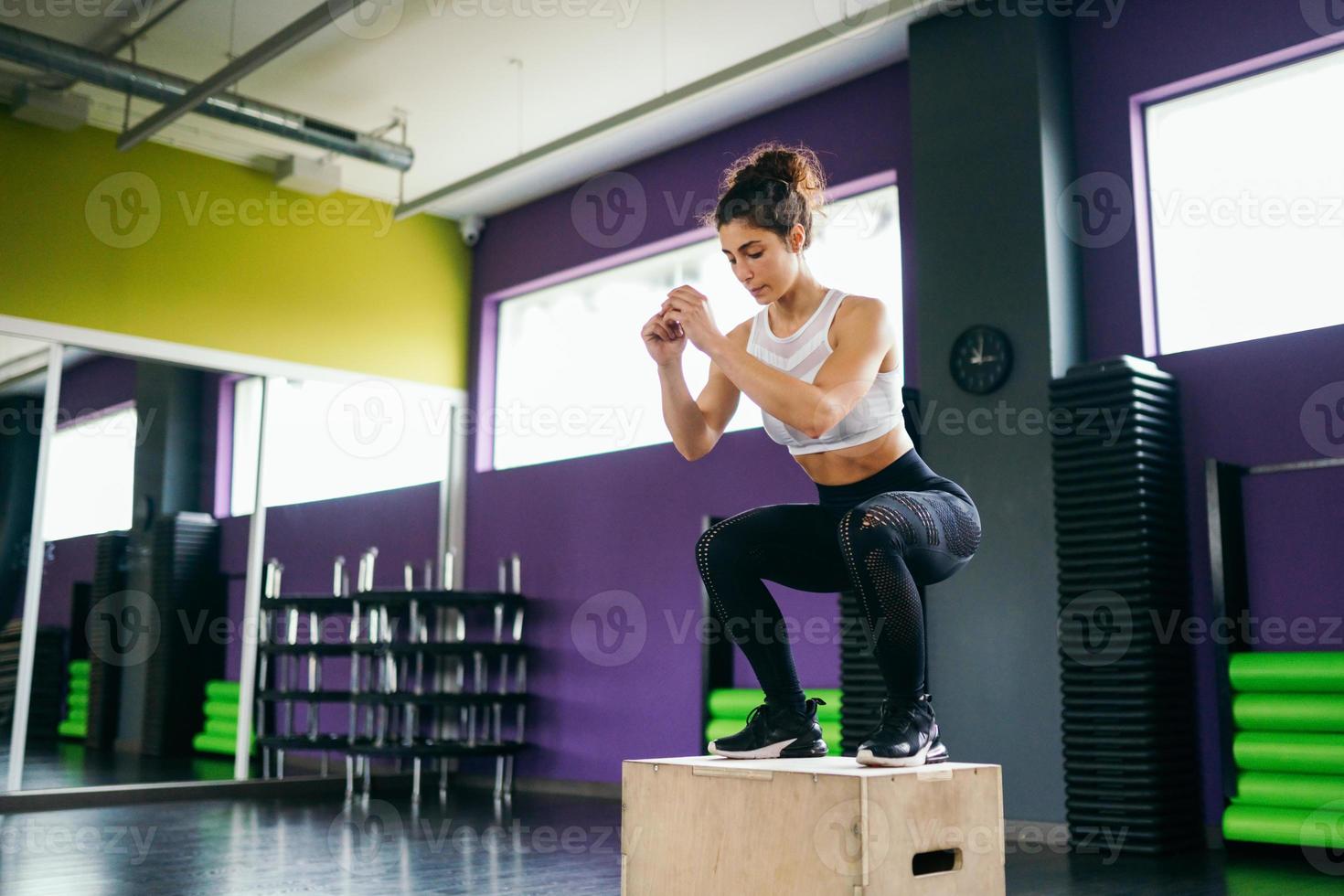 Athletic woman doing squats on box at the gym photo