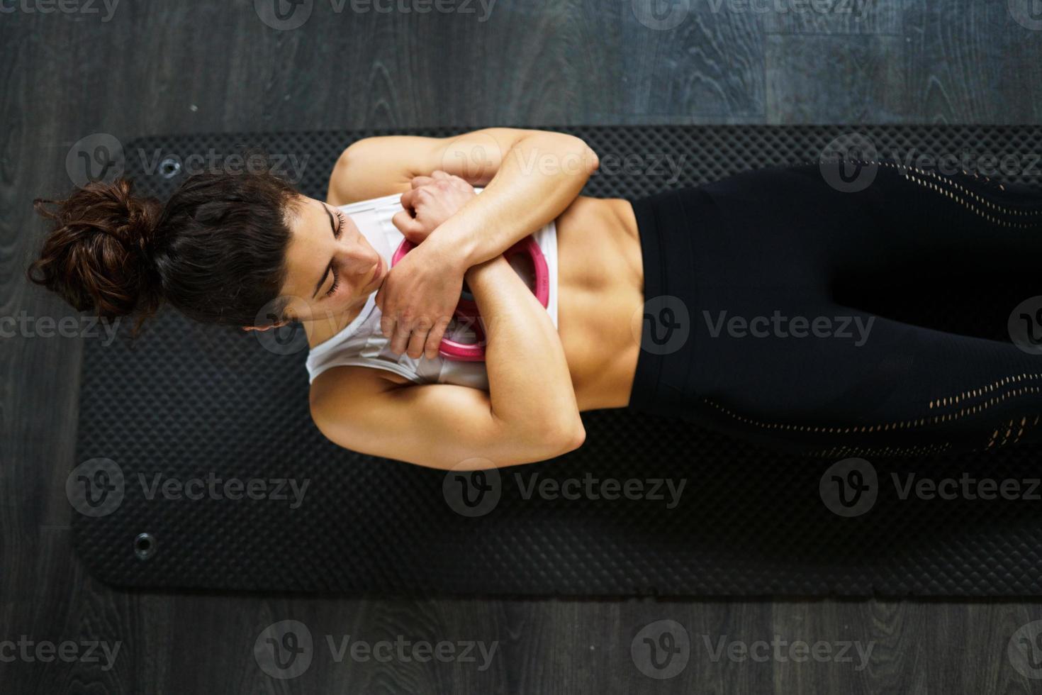 Young sportswoman on yoga mat doing situps in gym. photo