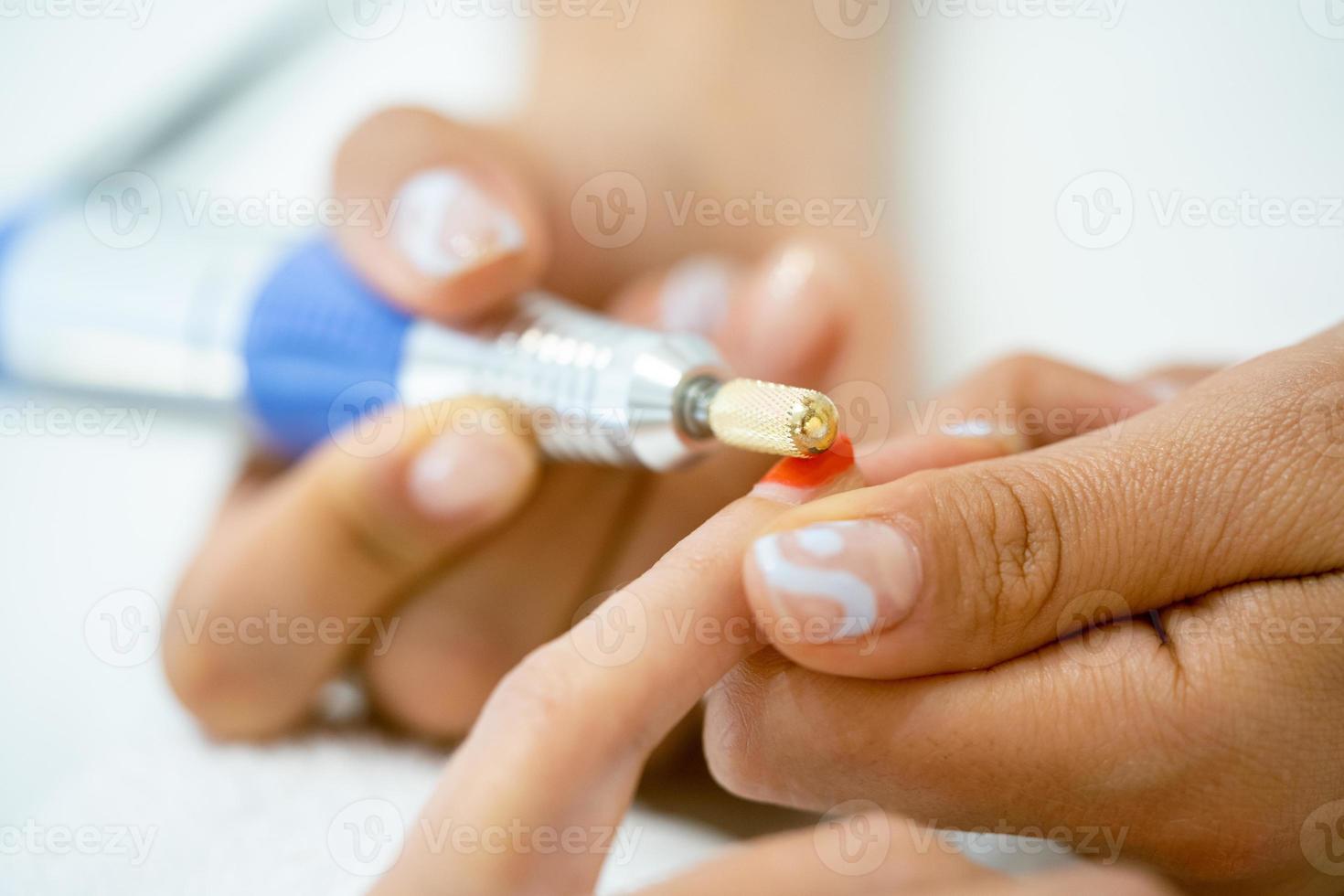 mujer en un salón de uñas recibiendo una manicura por una esteticista con. foto