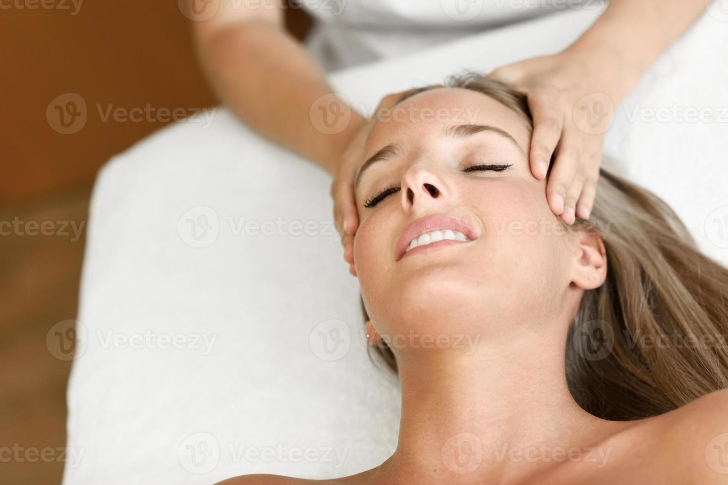 mujer joven recibiendo un masaje de cabeza en un centro de spa. foto