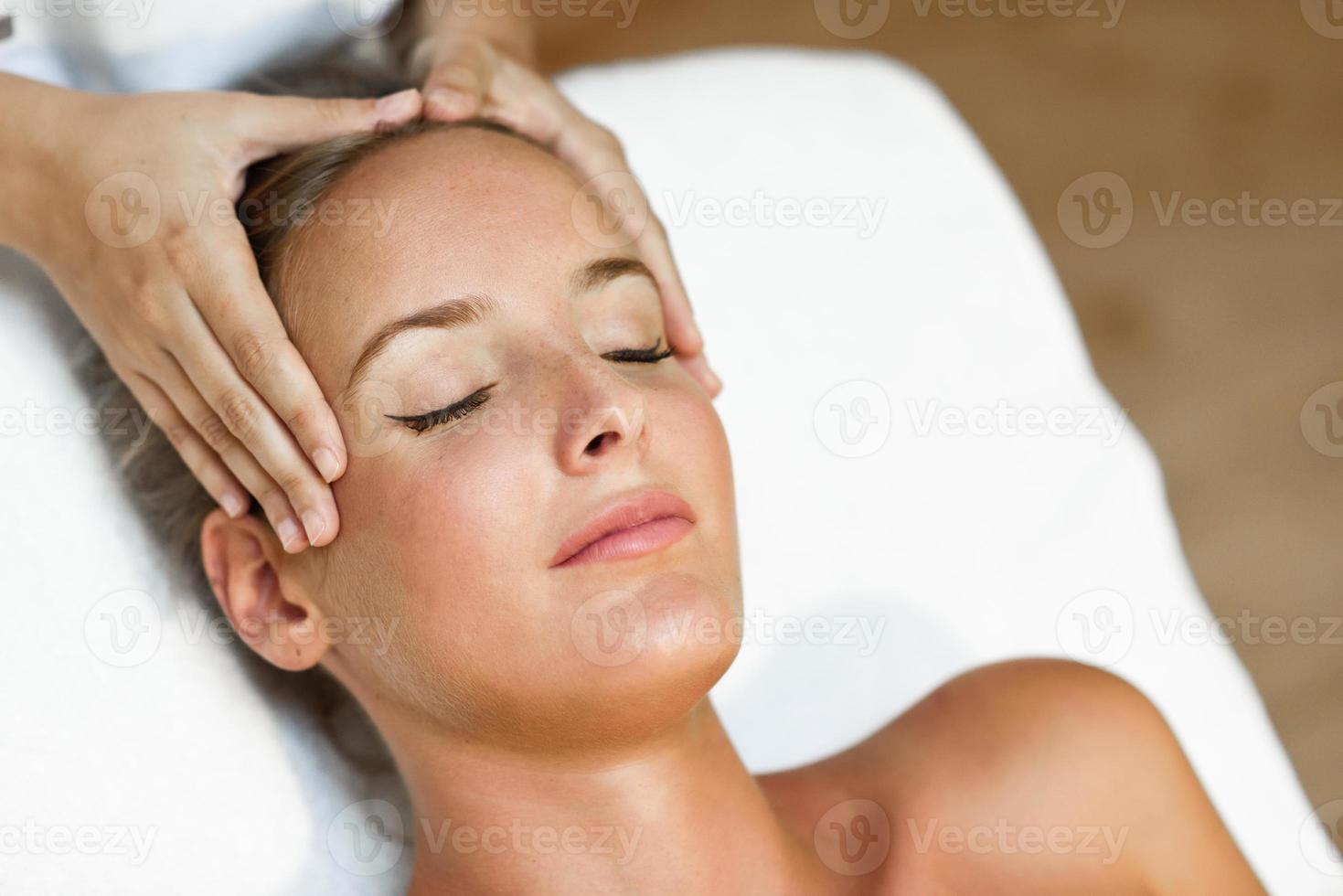 Young woman receiving a head massage in a spa center. photo