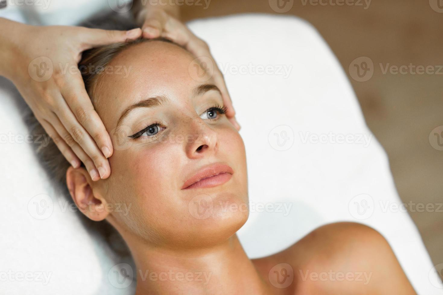 Young woman receiving a head massage in a spa center. photo