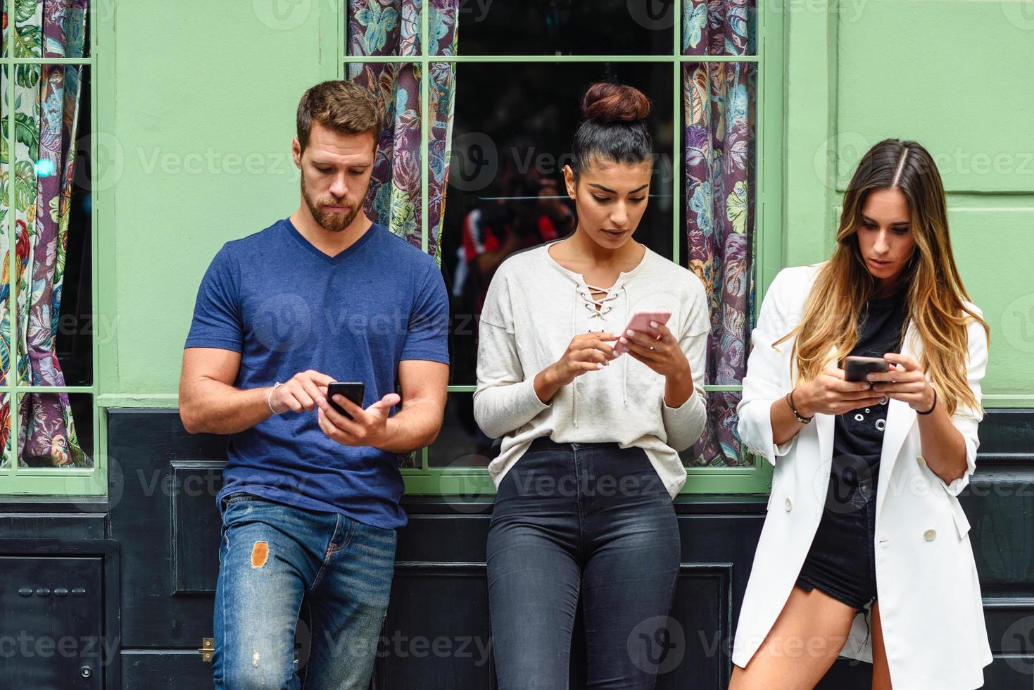 Multiracial group of people looking down at smart phone photo