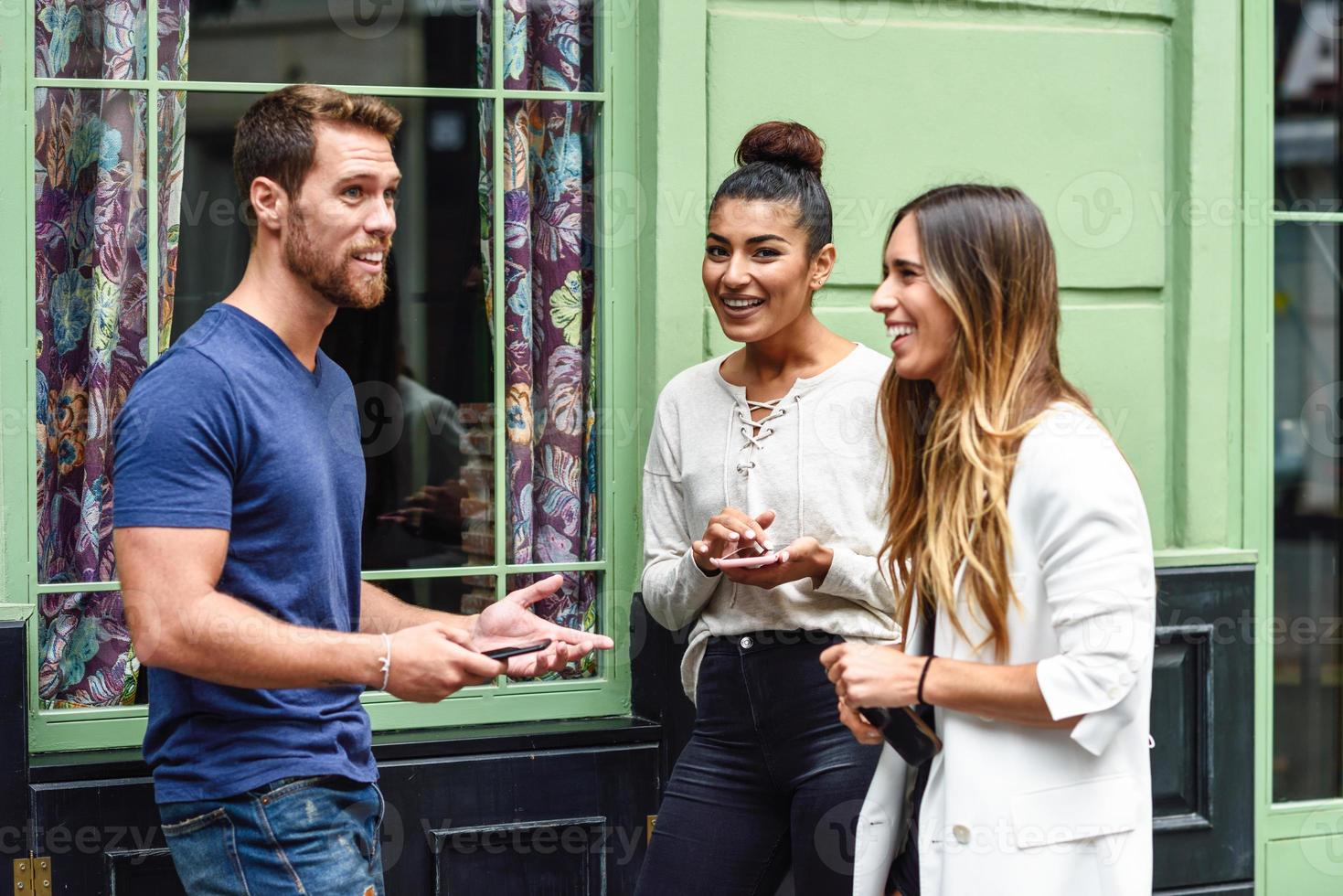 tres personas multiétnicas amigos hablando y sonriendo al aire libre foto