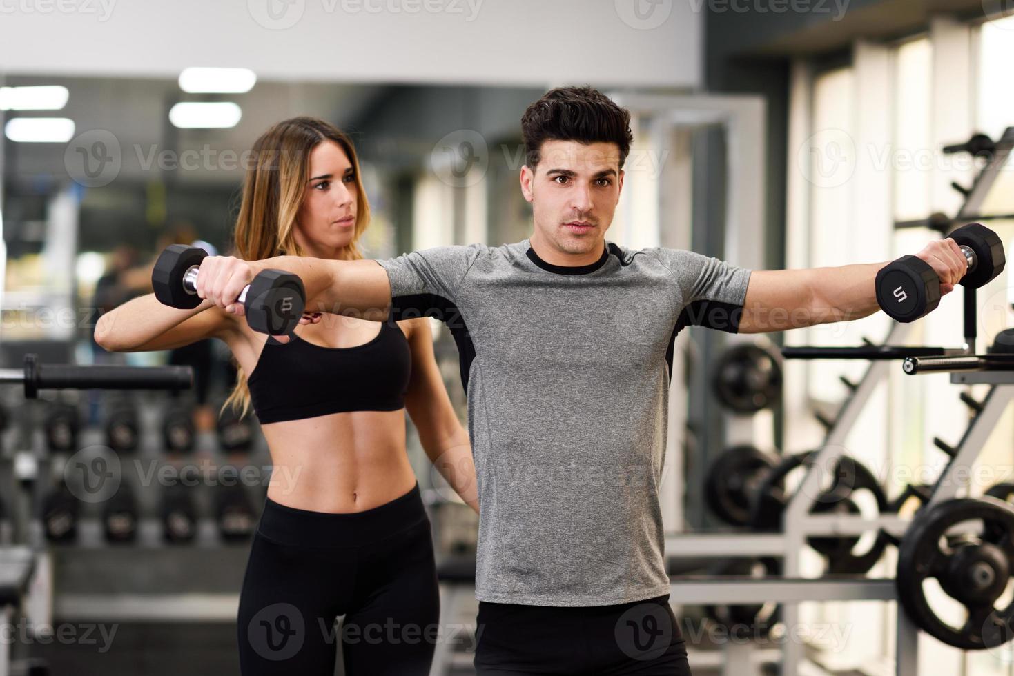 Personal trainer helping a young man lift weights photo