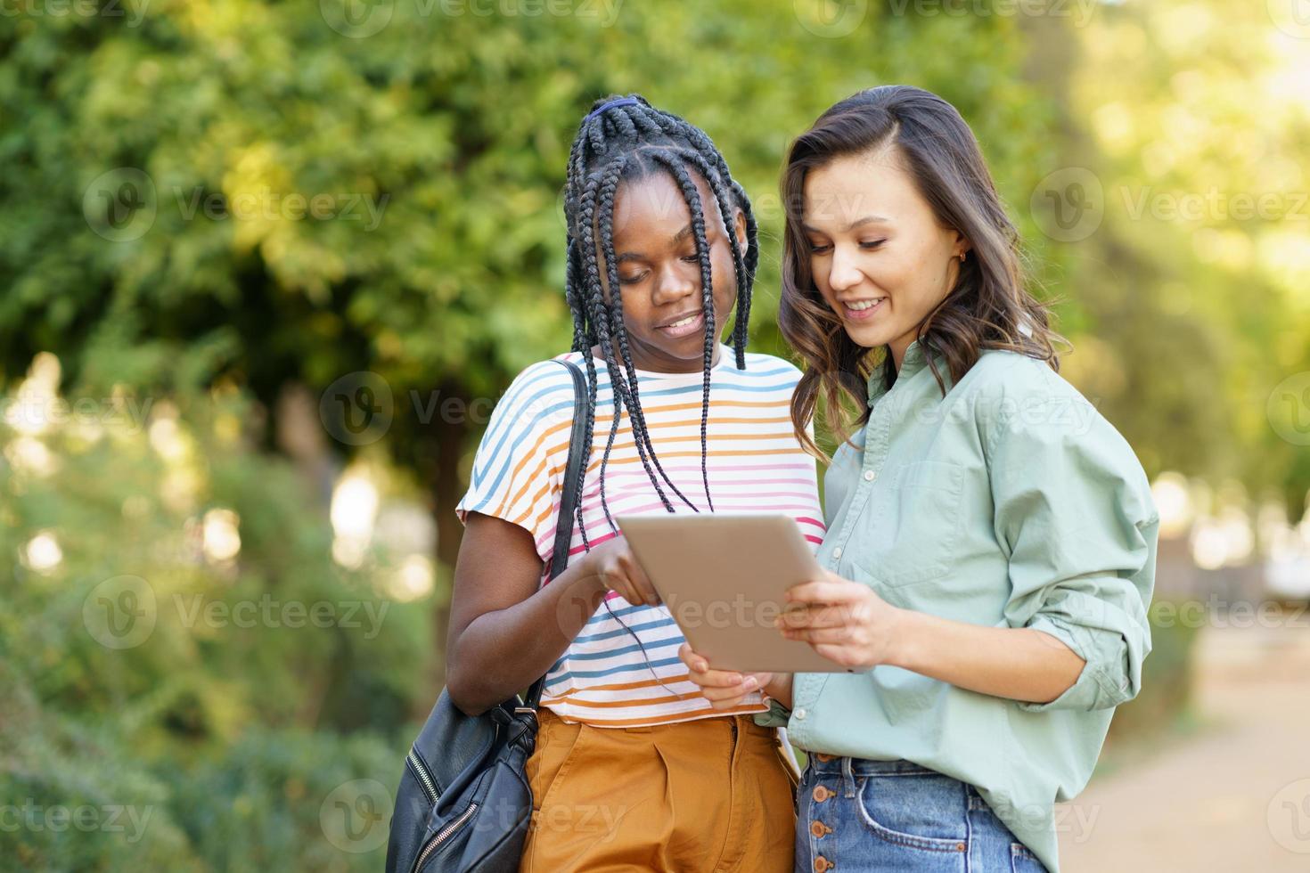 dos mujeres multiétnicas que consultan algo en una tableta digital. foto