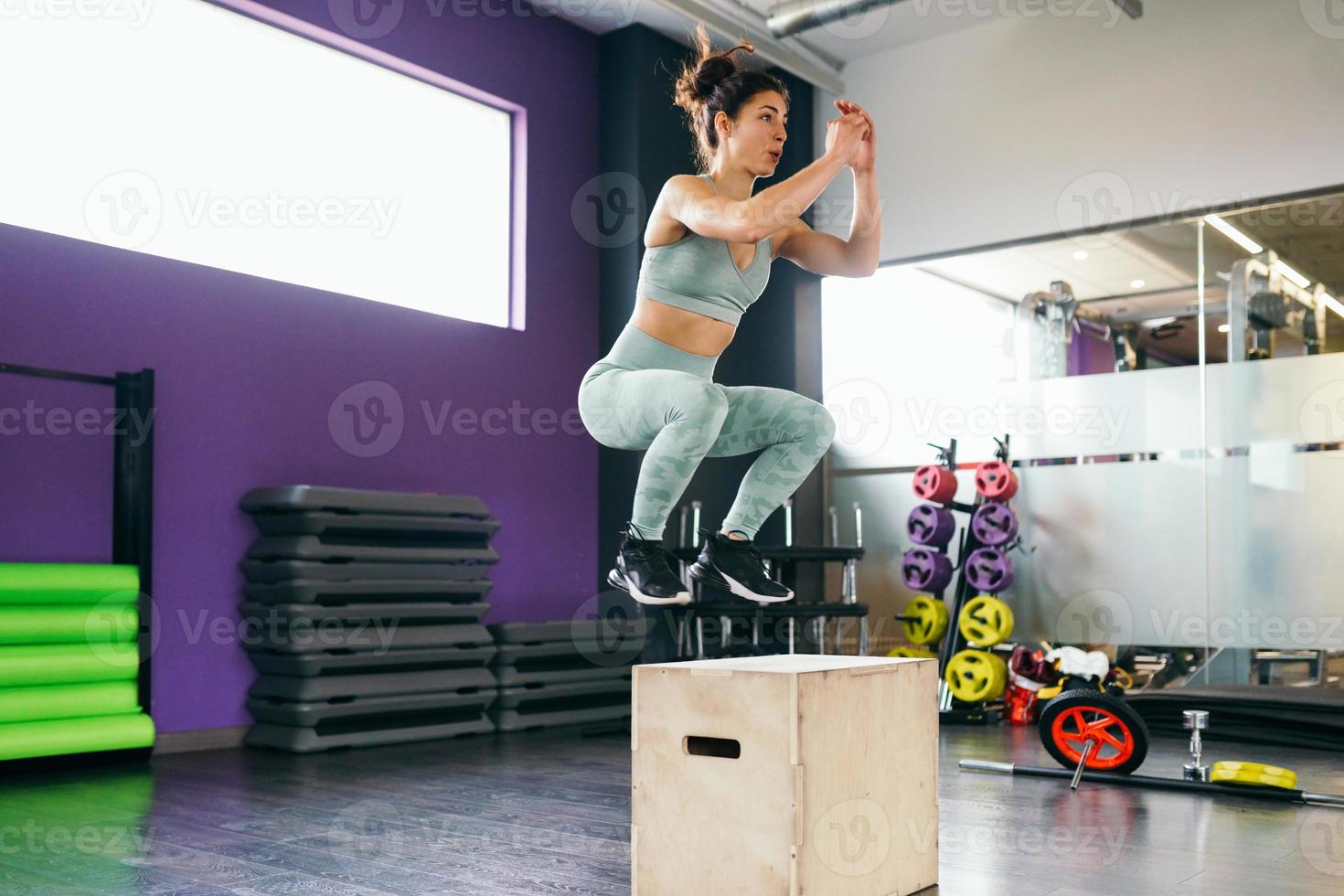 Caucasian female doing box jump workout at gym. photo