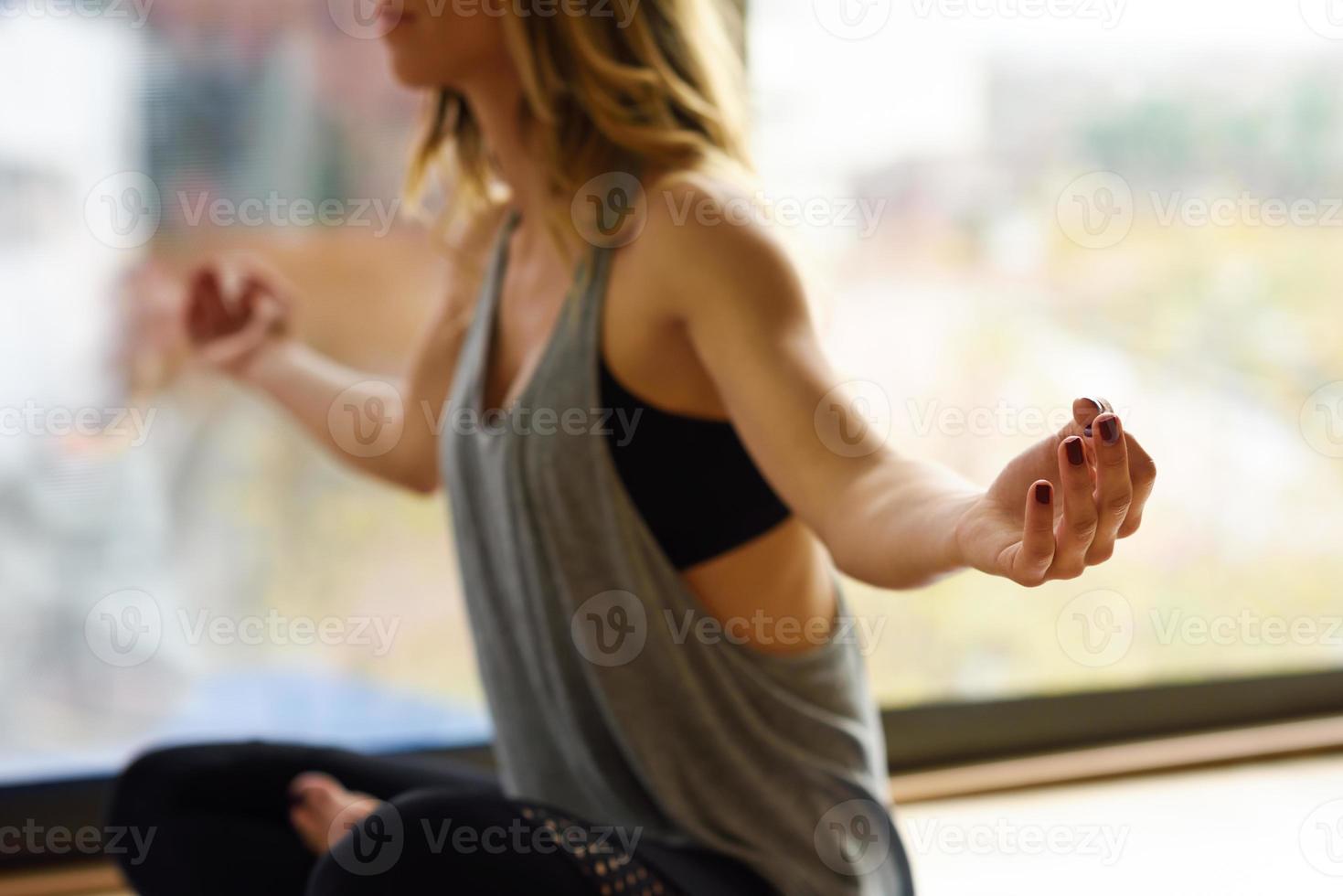 Young beautiful woman meditating in the lotus position in gym photo