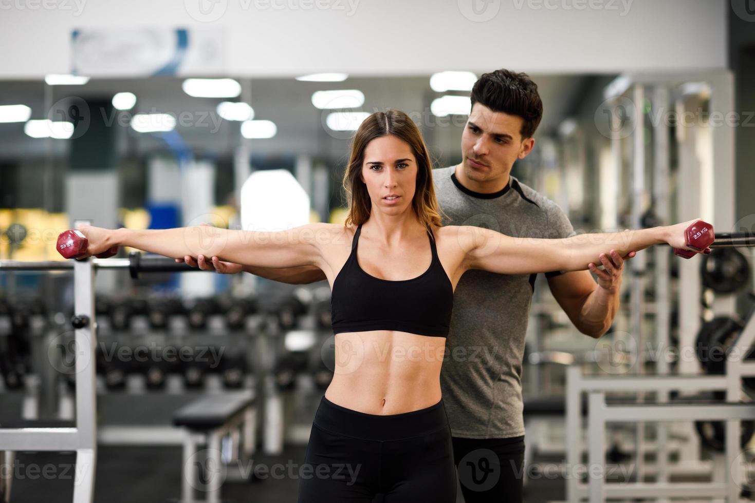 Personal trainer helping a young woman lift weights photo