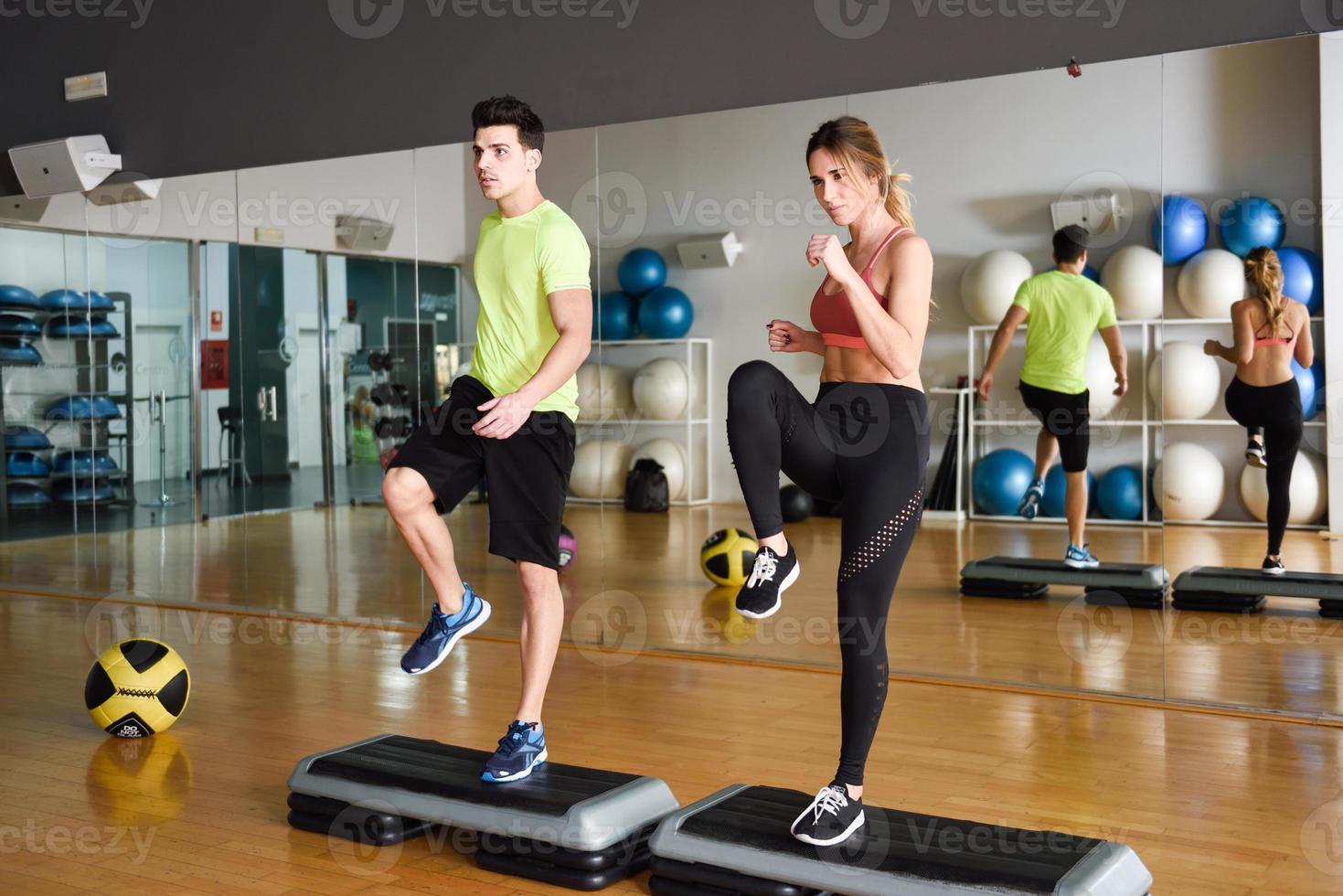 Two people working out with steppers in gym. photo