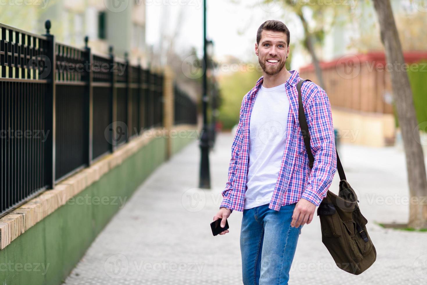 joven barbudo sonriendo en segundo plano urbano. concepto de estilo de vida. foto