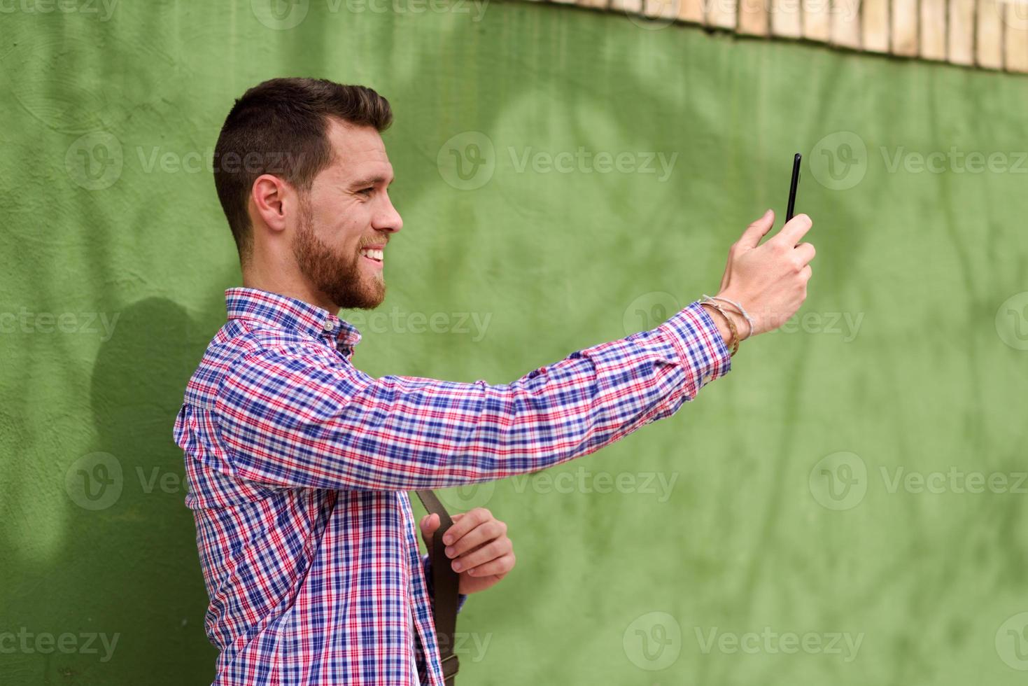 joven tomando fotografías con su teléfono inteligente en el contexto urbano. concepto de estilo de vida. foto