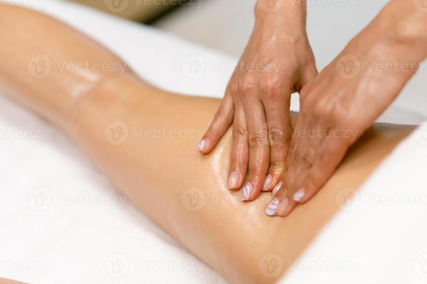 Beauty salon professional pouring oil from a massage candle on the back of his patient. photo