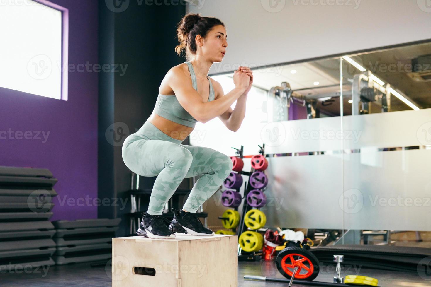 Caucasian female doing box jump workout at gym. photo