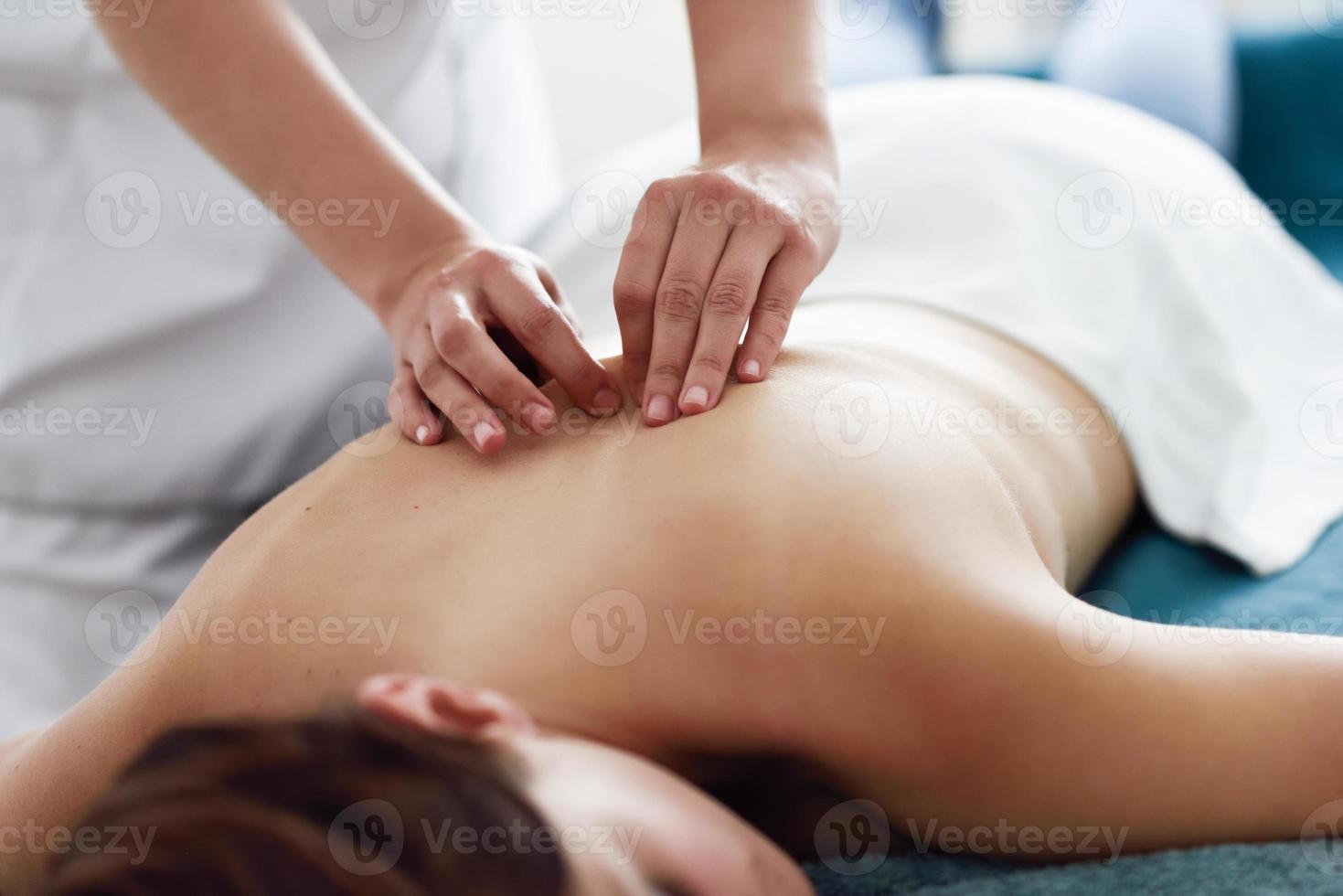 Young woman receiving a back massage by professional therapist. photo