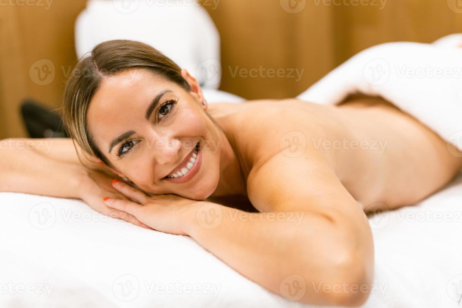 Middle-aged woman lying on a beauty parlour couch for a relaxing massage. photo