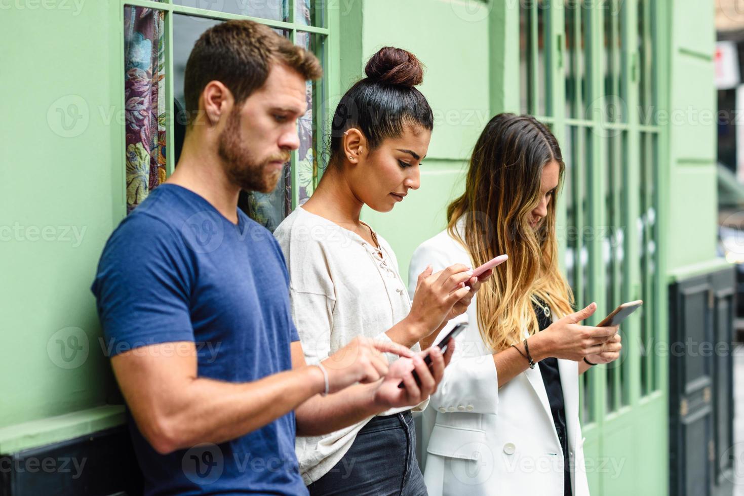 Multiracial group of people looking down at smart phone photo