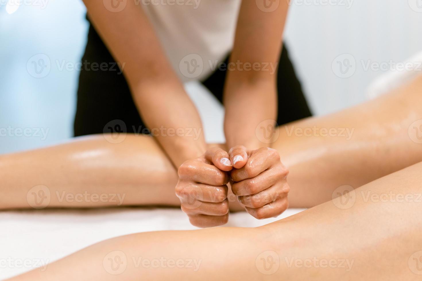 Beauty salon professional pouring oil from a massage candle on the back of his patient. photo