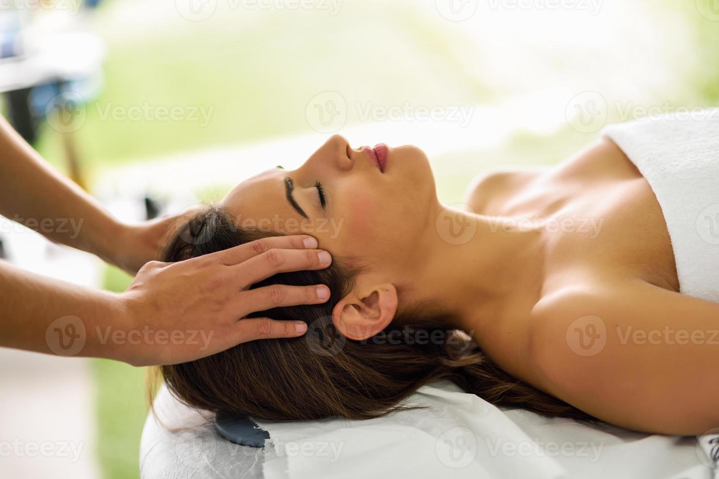 Young smiling woman receiving a head massage in a spa center. photo