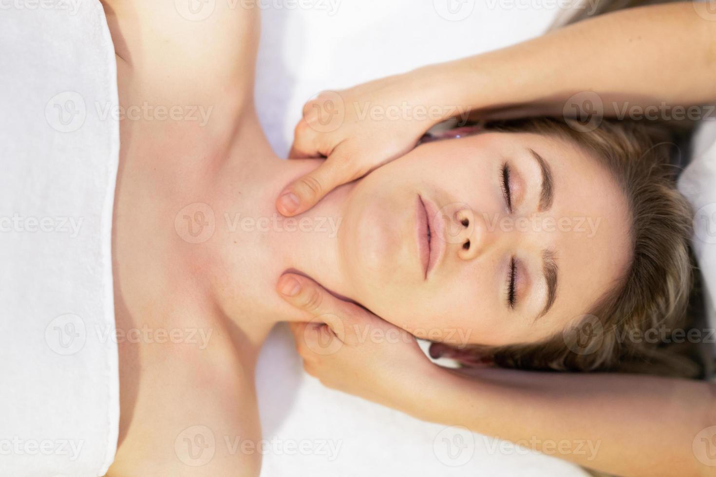 joven rubia recibiendo un masaje de cabeza en un centro de spa. foto